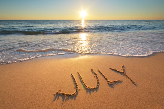 the word July written in the sand on the beach