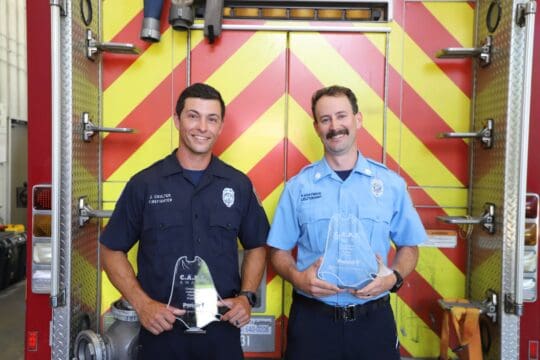 Firefighters in front of fire engine holding awards